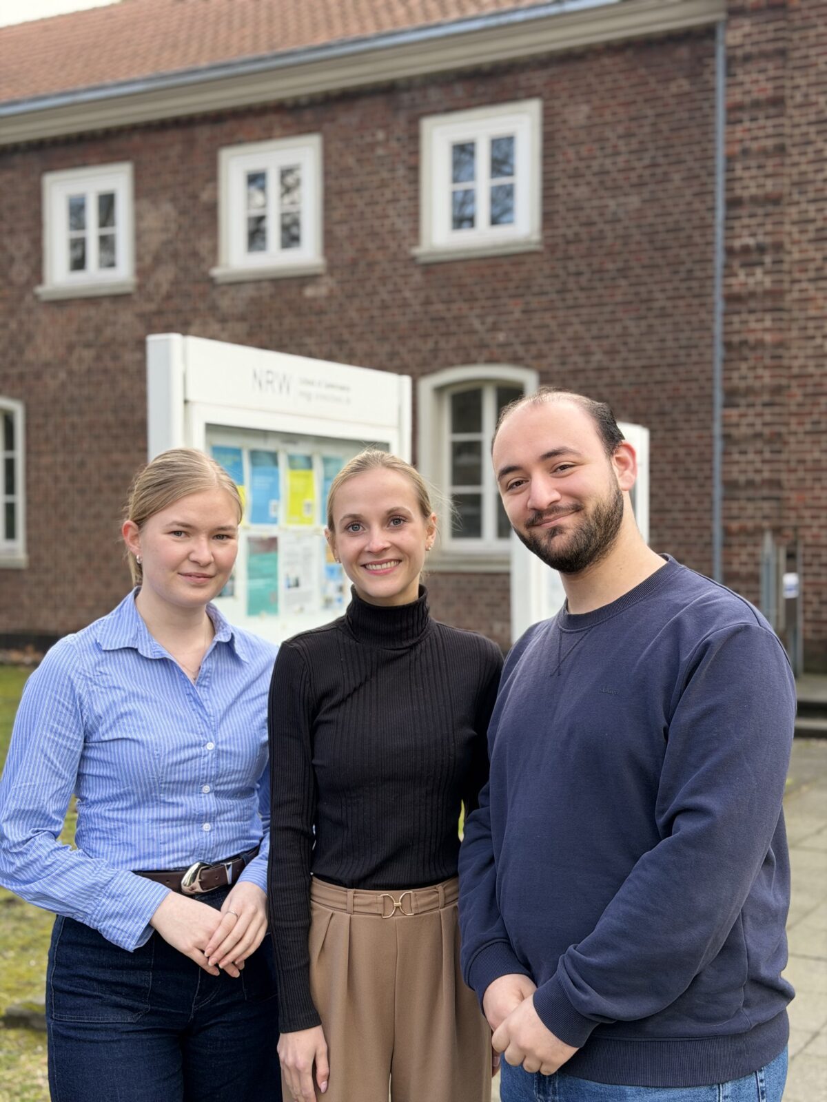 Foto der drei Autor*innen - Emily Schleicher, Alae Eddine Sanaa und Marleen Pooth - vor dem Gebäude der NRW School of Governance.
